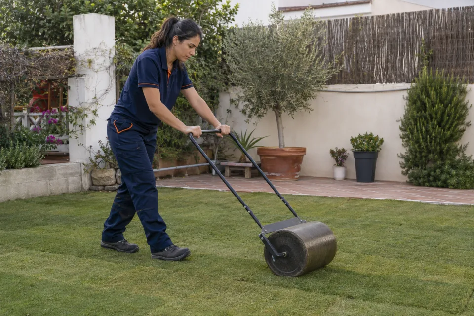 Técnica asentando con un rodillo manual las juntas de césped natural